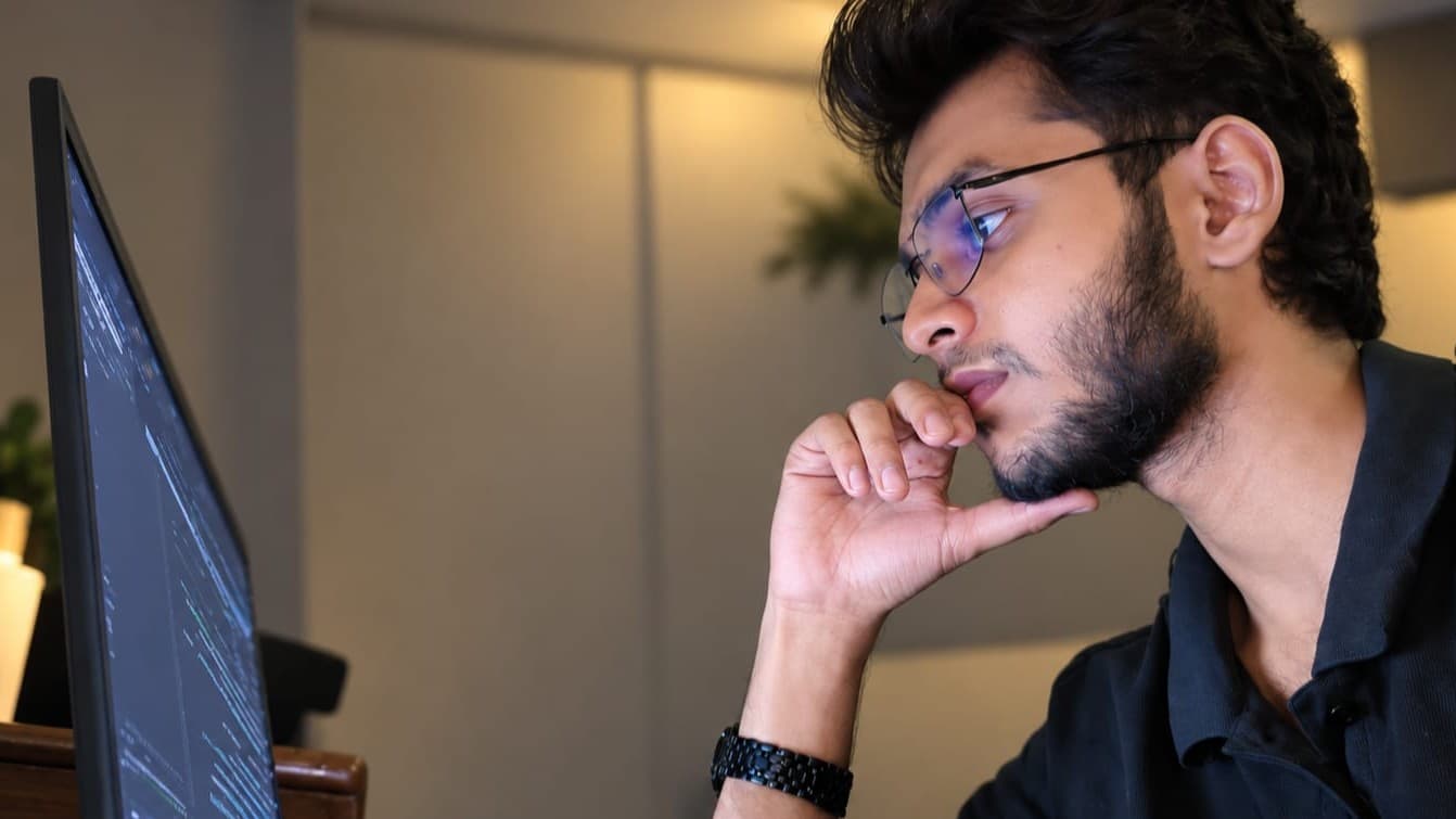 Yusuf Hussain at his desk, reading code on his monitor